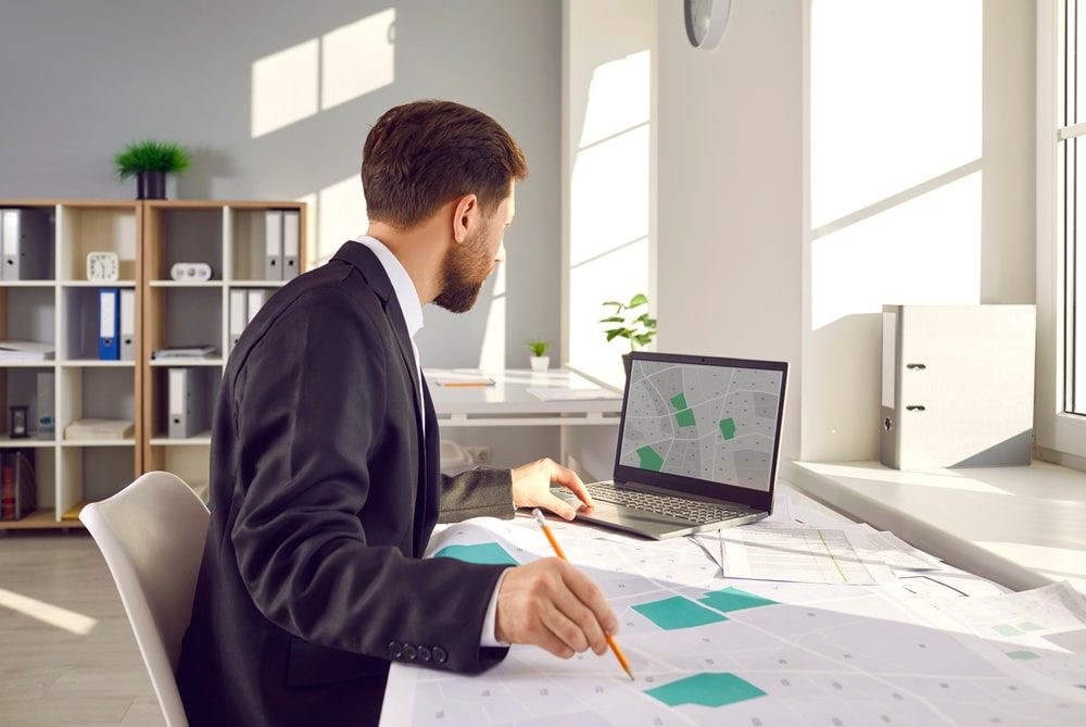 Man working on a computer calculating real estate property size