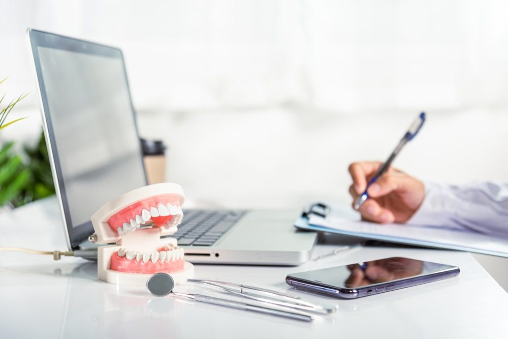 Virtual assistant working at a desk with dentistry related tools beside him