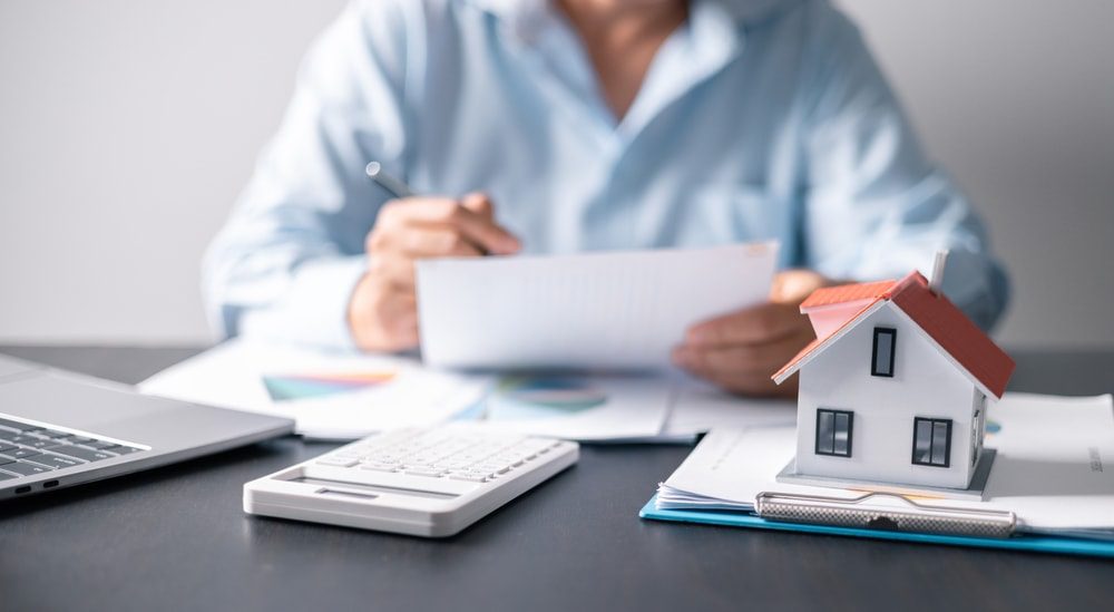 Man working at a desk calculating prices of real estate properties