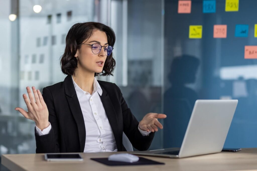 Woman wearing glasses conducting a serious virtual meeting